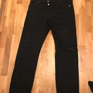 Levis 501 W33 L32 - Säljer här ett par Levi's 501 jeans i svart. Jeansen har en klassisk passform och är i gott skick. Perfekt för vardagsbruk eller speciella tillfällen. Se bilderna för detaljer. Jag är 187 cm och väger ca 75 kg som storleksreferens.