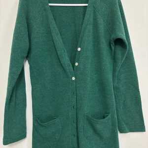 Grön kofta med knappar - Säljer en mysig grön kofta med långa ärmar och knappar framtill. Koftan har två praktiska fickor och är perfekt för kyligare dagar. Passar bra till både jeans och kjol.