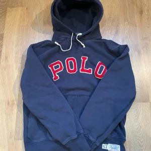 Mörkblå hoodie från Polo Ralph Lauren - Snygg mörkblå hoodie från Ralph Lauren med stor röd POLO text på bröstet. Tröjan är i Storlek S och är i fint skick! Priset är diskuterbart.