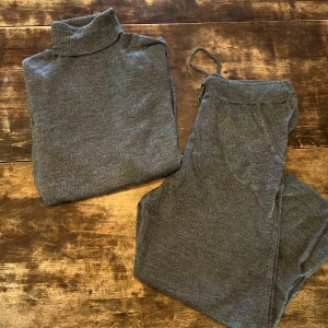 Set i merinoull, grå polotröja och byxor från Dagmar, stl S-M - Säljer ett set med en grå polotröja och matchande byxor från Dagmar i 100% merinoull. Tröjan har långa ärmar och en klassisk polokrage, perfekt för kyligare dagar. Byxorna har en bekväm passform med dragsko i midjan och mudd nedtill. Innerbenslängden på byxan är 70 cm. Stl är M, men liten i storleken. Setet är i gott skick och perfekt som både myskläder, samt underställ i skidbacken, på vandringen eller sovkläder för kallare dagar.