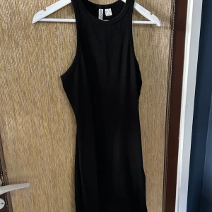 Svart ärmlös klänning - Säljer en snygg svart ärmlös klänning i storlek S. Klänningen är tight och perfekt för fest eller en utekväll. Den är enkel men stilren och kan matchas med olika accessoarer för att skapa olika looks. Den är ungefär knä lång. 