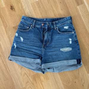 Jeansshorts i mörkare tvätt och i ”sliten” stil. 