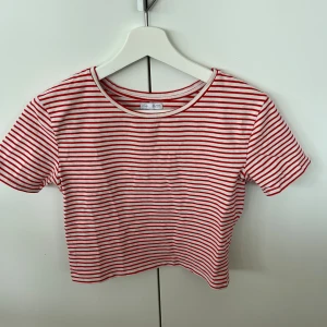 Randig T-shirt från Zara - Jättefin vintage modell av Zaras randiga t-shirt. Lagom röd färg, inte skrikig färg liksom. Sitter jättefint och är stretchig. Står storlek L på lappen men sitter som en S