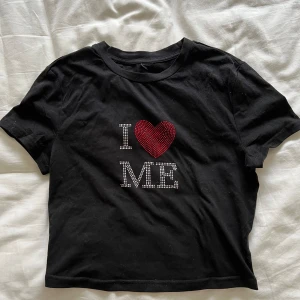 Svart t-shirt med texten 'I ❤️ ME' - Säljer en svart t-shirt med texten 'I ❤️ ME' i vita och röda paljetter. T-shirten är kortärmad och har en normal passform. Perfekt för en avslappnad och självsäker stil. Köp direkt eller ge prisförslag 💛