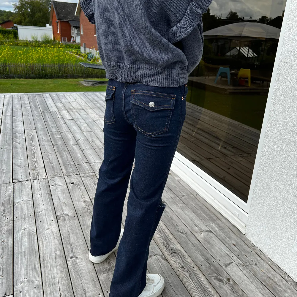 Säljer ett par snygga mörkblå jeans med slitningar på knäet. De har en straight passform och är midwaist. Perfekta för en avslappnad stil och passar till det mesta. Sköna och trendiga!. Jeans & Byxor.