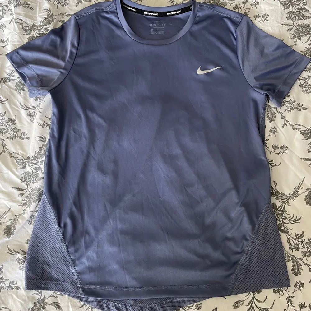 Säljer en lila tränings-t-shirt från Nike. Använd ett fåtal gånger, men har lite små defekter pga tvättmaskin (se bild 4-5), men inget som syns jätte tydligt! . Sportswear.