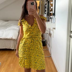 Klänning - Såå söt gul blommig klänning med volanger och knytning i midjan. Det är en XS men super flexibel storlek och passar mig som brukar ha S utan problem 💛.