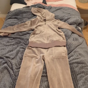 Beige velour hoodie och byxor - Säljer en supermjuk och bekväm beige velour hoodie med matchande byxor. Hoodien har dragkedja och en mysig huva, perfekt för chilliga dagar. Byxorna har en elastisk midja och praktiska fickor både fram och bak. Setet är i bra skick och perfekt för en avslappnad stil.