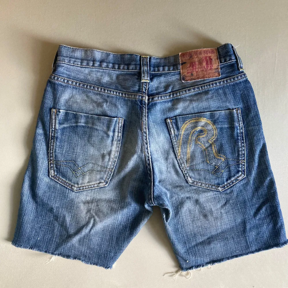 Säljer ett par coola. slitna blå jeansshorts med råa kanter. Vintage från 2000. De har en klassisk femficksdesign och en knappgylf. Storlek 36 (barn).. Shorts.