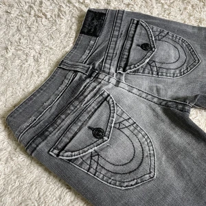 Vintage True Religion jeans - Snygga vintage True Religion jeans i sällsynt modell! Gråa med svarta detaljer, lågmidjade och lätt bootcut. 😍 Mått finns på bild, jag är 167cm. 🫶🏻 Använd gärna köp nu !! 