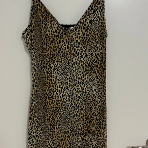 Leopardmönstrad klänning - Säljer en supercool leopardmönstrad klänning som är perfekt för en utekväll eller fest. Klänningen är ärmlös och har en v-ringad design som ger en snygg look. Materialet känns mjukt och bekvämt mot huden.