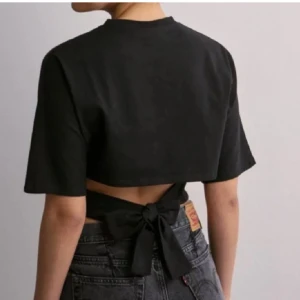 T-shirt nelly  - Så snygg slutsåld t-shirt med rosett i ryggen från Nelly! Svart, XS och använd fåtal gånger 💕 