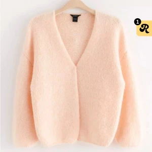 Ljusrosa stickad kofta från Lindex - Supermysig ljusrosa stickad kofta från Lindex. Perfekt för kyliga dagar med sin fluffiga och mjuka textur. Den har en v-ringad design och långa ärmar, vilket gör den både stilren och bekväm. Näst till oanvänd