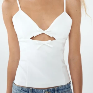 Stretchtopp med cut out och rosetter i  - En vit topp från Zara i storlek M. Ny skick, aldrig använt. Den är normal i storleken men jag tyckte inte den passa bra på mig. 