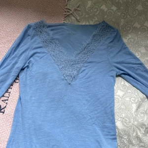 Blå långärmad topp från Intimissimi - Säljer en superfin blå långärmad topp från Intimissimi. Den har en vacker spetsdetalj runt den v-ringade halsen och vid ärmsluten. Inga defekter eller skador, nästan helt oanvänd. Använd få gånger💙