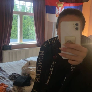 Svart pufferjacka från Moncler - Säljer en svart pufferjacka från Moncler. Den är supervarm och perfekt för vintern. Jackan har långa ärmar och en cool logga på ärmen. Insidan har en röd dragkedja och en unik serietidningsdesign. Perfekt för att hålla stilen när det är kallt ute!