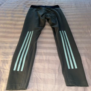 Grå leggings med svarta detaljer - Säljer ett par adidas leggings i grå/grön färg med tre ränder på varje bakben. perfekta för träning eller en avslappnad dag. Materialet är mjukt och stretchigt (bomull). Storlek S/34-36. I använt skick. 