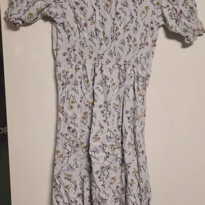 Blommig klänning - Säljer en superfin blommig klänning i ljus färg. Den har korta ärmar och ett härligt blommönster i olika färger som ger en somrig känsla. Perfekt för vår och sommar! Är använd 1 gång.  Priset kan diskuteras