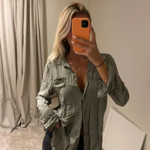 Militärgrön skjorta - Säljer en skitsnygg militärgrön skjorta från Mirelle i lyxigt tyg! Behöver obvi strykas!! Men annars Toppskick! Står ingen storlek men skulle säga att den passar XS-M💘