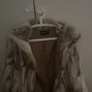 Pälsjacka från Hollies - Säljer en lyxig pälsjacka från Hollies i storlek L. Jackan har en naturlig färgton med inslag av beige och brun, perfekt för att hålla dig varm och stilren under kyliga dagar. Den har en klassisk design med en mjuk och fluffig känsla. Priset kan diskuteras! Tror heller inte denna modellen säljs längre. Passar mig som har S! Den blir oversized:) och de finns knappar så man kan stänga den.