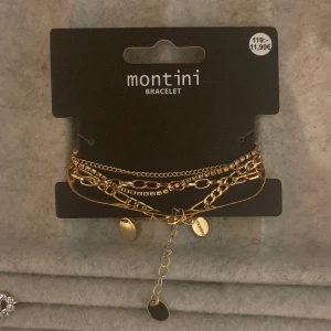 Guldarmband från Montini - Snyggt guldarmband från Montini med flera kedjor och små berlocker. Perfekt för att lägga till en touch av elegans till din stil. Armbandet har en justerbar kedja för att passa olika storlekar.