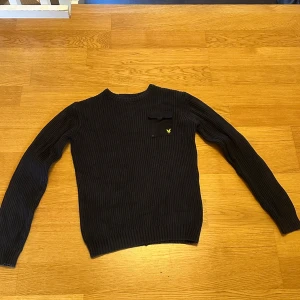 Mörkblå stickad tröja från Lyle & Scott - Säljer en svart stickad tröja från Lyle & Scott. Tröjan har en ribbad design och en liten bröstficka med en gul logga . Storlek står 14/15 år men passar även herr storlek S. Pris går att diskutera vid snabb och effektiv affär 