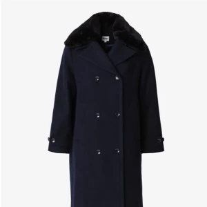 Mörkblå kappa med fuskpäls - Elegant mörkblå kappa med dubbelknäppning och en lyxig fuskpälsdetalj vid kragen. Perfekt för kyliga dagar med sin långa design och stilrena look. Kappan har långa ärmar och en klassisk passform.                                      Ny oanvänd från Indiska storlek 36.                                         Nypris 1500kr