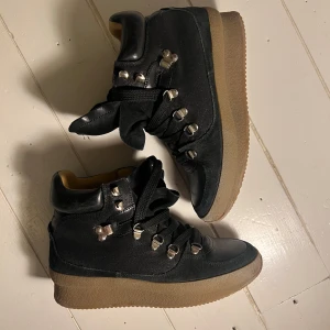 Isabel Marant hiking boots  - Snygga svarta sneakers från Isabel Marant med robust sula och snörning. Skorna har metalliska detaljer och en kombination av skinn och mocka. Perfekta för en stilren look. Nypris ca 5000k mitt pris 2000kr