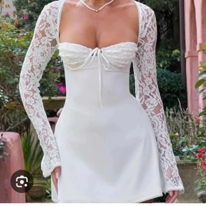Vit spetsklänning med snörning -  Vit klänning med långa spetsärmar och snörning i ryggen. Klänningen har en tight passform och en söt knytning framtill. Perfekt till tex studenten som jag hade min klänningen till. Endast andvänt en del av dagen. skriv om du är intresserad så kan jag skicka fler bilder på klänningen 🌸💖💖