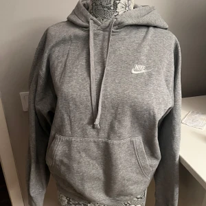 Grå hoodie från Nike - Säljer en klassisk grå hoodie från Nike med justerbar huva och känguruficka. Perfekt för en avslappnad stil. Den har en broderad Nike-logga på bröstet och långa ärmar. Detta är från herr-avdelning men jag har använt den fåtal utan problem. 