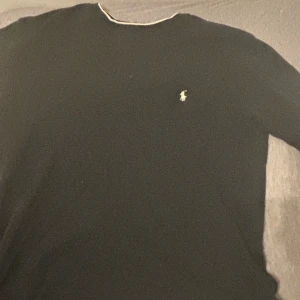 Svart långärmad tröja från Ralph Lauren - Säljer en stilren svart långärmad tröja från Ralph Lauren med det klassiska logotypen broderad på bröstet. Perfekt för en avslappnad men ändå elegant look. Passar i både M och L.