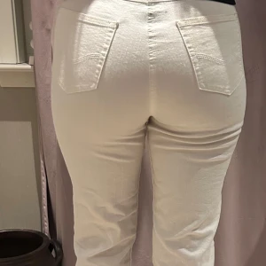 Vita jeansbyxor - Snygga vita jeansbyxor med hög midja och raka ben. Perfekta för en stilren look. De har klassiska femficksdetaljer och en knappgylf framtill.