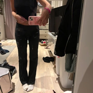 Svarta byxor med rak passform - Snygga svarta byxor med rak passform och låg midja. Perfekta för en stilren look. Byxorna har en diskret detalj vid midjan och är gjorda i ett bekvämt material.