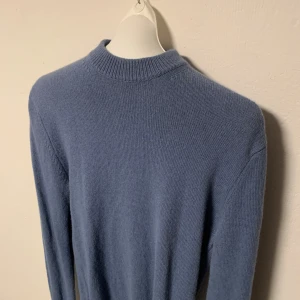 Blå stickad tröja från Mango - Säljer en stilren blå stickad tröja med långa ärmar och ribbade kanter. Perfekt för kyligare dagar och enkel att matcha med olika outfits. Storlek S.