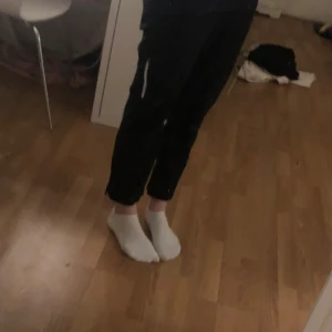 Svarta byxor med dragkedja - Säljer ett par svarta byxor med dragkedja på sidan. Byxorna har en avslappnad passform och är perfekta för en casual look. De är bekväma och lätta att bära.