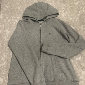 Grå hoodie från Lacoste - Säljer en spliter ny lacoste zip hoddie, väldigt stilig och funkar till de mesta 