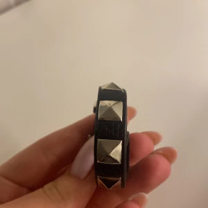Valentino armband - Snyggt svart bälte med silverfärgade nitar. Tillverkat i skinn och har ett klassiskt spänne. Perfekt för att ge en edgy touch till din outfit.