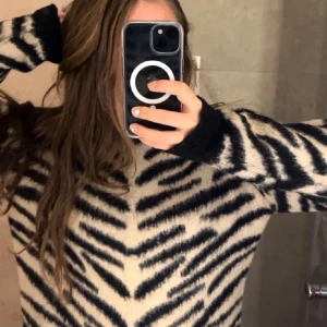 Zebramönstrad tröja - Säljer en trendig zebramönstrad tröja med långärmade ärmar. Tröjan har en bekväm passform och är perfekt för kyligare dagar.