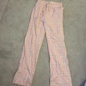 Säljer ett par bekväma rosa byxor från Gina Tricot med rutigt mönster. Byxorna har en elastisk midja med snörning för justerbar passform. Perfekta för en avslappnad stil. Omsydda längst ner så de blir längre 