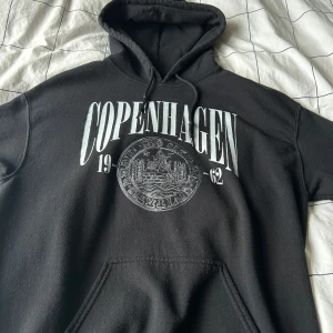 Svart hoodie  - Säljer en svart hoodie med stort 'Copenhagen' tryck på framsidan. Perfekt för en avslappnad stil.  Storlek M. Kvitto finns. 