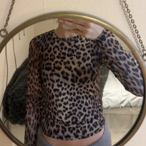 Leopardmönstrad topp från Gina Tricot - Säljer en snygg leopardmönstrad topp från Gina Tricot i storlek XS. Toppen har långa ärmar och en tight passform, perfekt för att ge en trendig look. Materialet är i mesh.