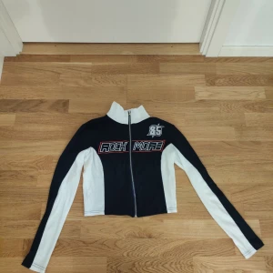 Marinblå och vit top med dragkedja från Yesstyle  - Snygg marinblå och vit top från Yesstyle med dragkedja framtill och textdetaljer på bröstet. Jackan har en croppad passform.. Det står M i storlek men passformen är till 34-36.