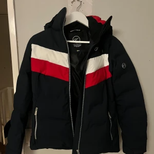 Svart dunjacka från Five Seasons - Säljer en mörkblå dunjacka från Five Seasons med röd och vit rand över bröstet.  Använd 1 gång och är i jätte fint skick!