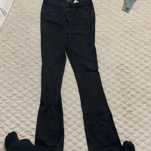 Svarta bootcut jeans - Snygga svarta bootcut jeans med hög midja. Perfekta för en stilren look. De har en klassisk design med dragkedja och knappar framtill.