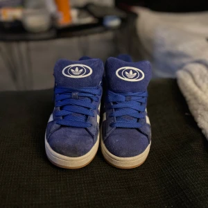 Blå Adidas campus - Snygga blå sneakers från Adidas med vita detaljer och klassiska tre ränder på sidan. Skorna har snörning och en bekväm sula. Perfekta för en avslappnad stil.