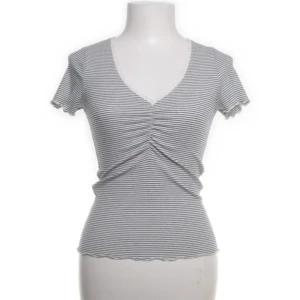 Randig topp från Holly & Whyte - Säljer en randig topp från Holly & Whyte by Lindex i storlek XS. Toppen har en v-ringad design med korta ärmar och rynkdetalj framtill. ❤️