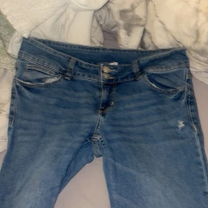 Blå jeans med broderade bakfickor - Snygga blå jeans från Divided i storlek 42. De har en klassisk femficksdesign med unika broderade detaljer på bakfickorna. Perfekta för en avslappnad stil med en touch av personlighet.