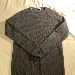 Grå stickad tröja från Selected Homme - Säljer en stilren grå stickad tröja från Selected Homme. Tröjan har en klassisk rund hals och långa ärmar, perfekt för kyligare dagar. Materialet är mjukt och bekvämt, vilket gör den till ett utmärkt val för både vardag och avslappnade tillfällen. Sitter som M fast den är S
