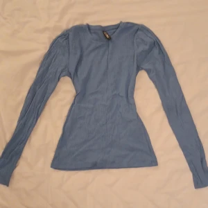 Blå ribbad långärmad topp - Snygg blå ribbad topp från pieces med långa ärmar. Perfekt för en stilren look. Passar bra till både jeans och kjol.