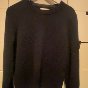 Svart tröja från Stone Island - Säljer en stilren svart tröja från Stone Island. Tröjan har en klassisk design med rund hals och långa ärmar. Perfekt för en avslappnad och trendig look. Stone Island-loggan sitter på ärmen för en extra touch av stil.